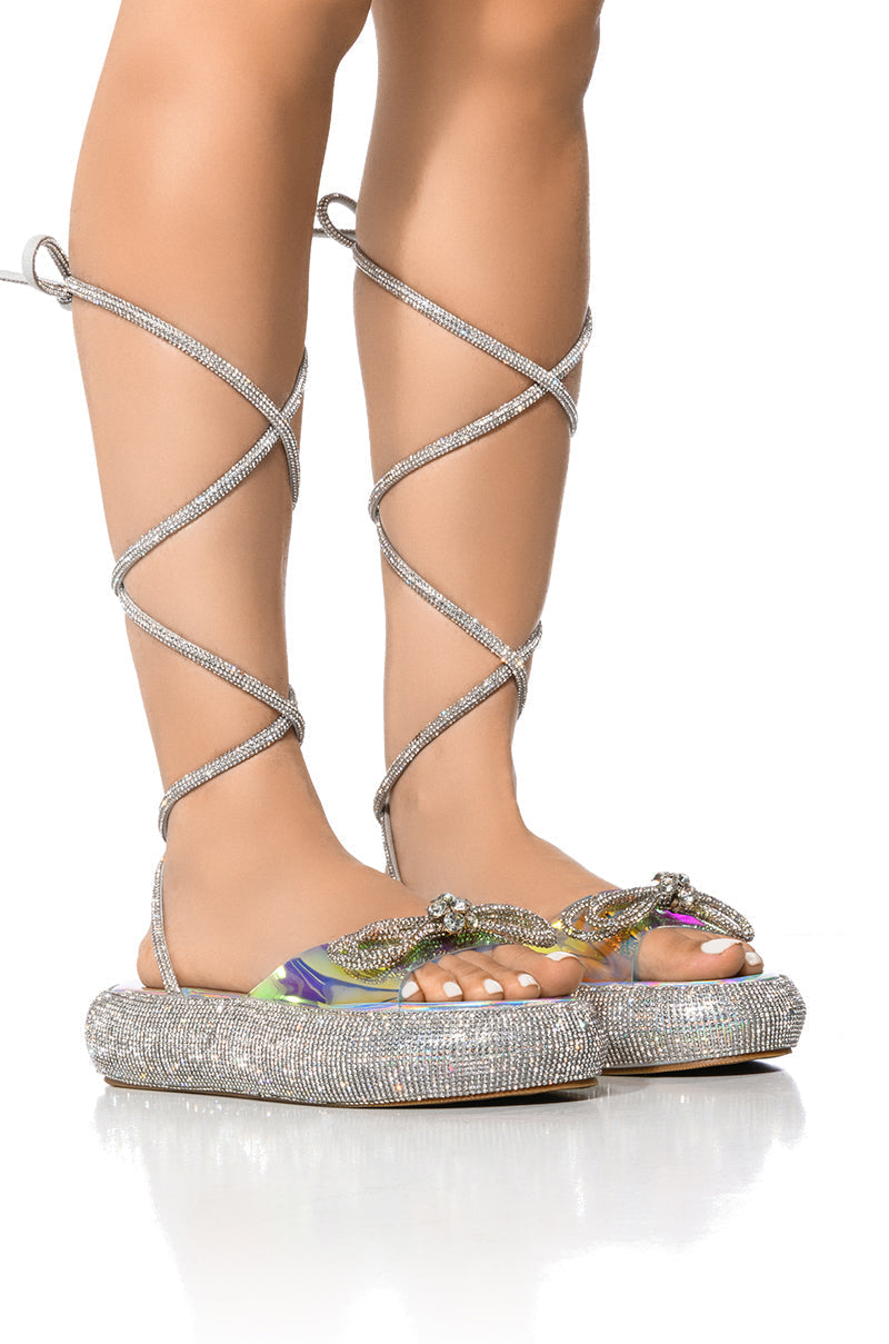 OUTSHINE EMBELLISHED BOW LACE UP FLAT SANDAL IN HOLO